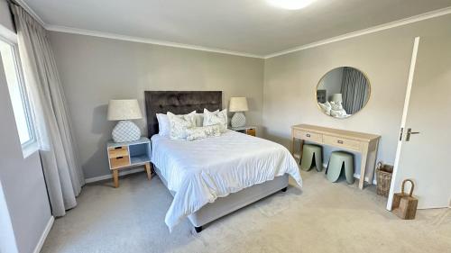 普利登堡湾Greenpoint Mews 17, Plettenberg Bay的卧室配有白色的床和镜子