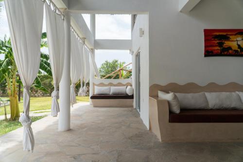瓦塔穆Rafiki Tamu Residential Resort的门廊配有白色窗帘和秋千