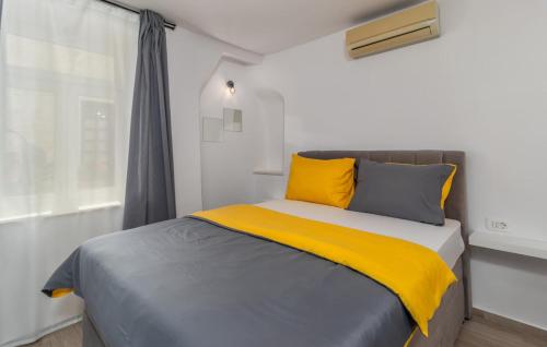 拉布Rab Stari grad的一张带黄色和灰色枕头的床和窗户