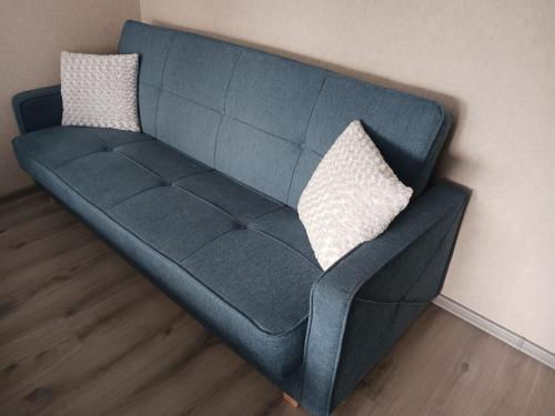 陶格夫匹尔斯Kandavas Apartments的墙上的蓝色沙发,配有两个枕头