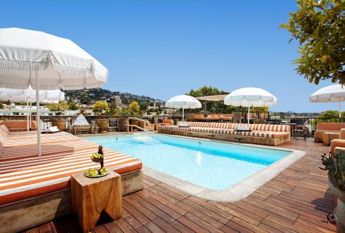 洛杉矶贝提艾米塔基酒店的一座大楼内的游泳池,配有椅子和遮阳伞