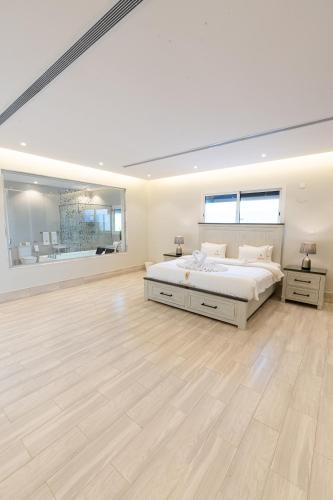 杜拉特阿拉尔Tiffany Beach的一间白色卧室,配有一张大床和硬木地板