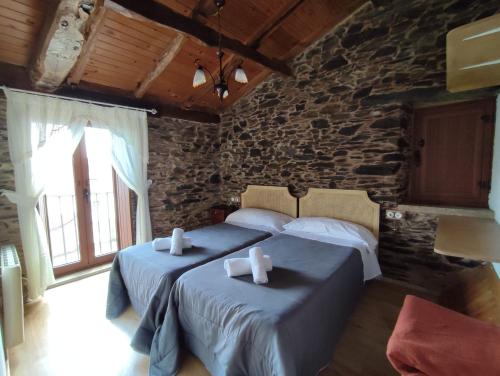 阿尔苏阿VILA PEREGRINA-taxi gratis的一间卧室设有两张床和石墙