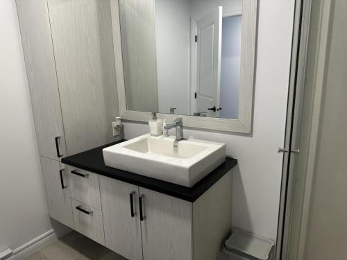 魁北克市Refuge urbain à Beauport的浴室设有白色水槽和镜子
