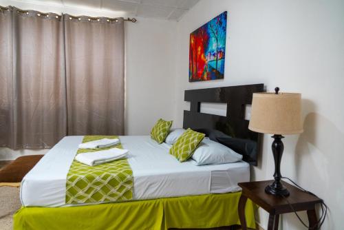 圣萨尔瓦多圣贝尼托-索娜罗莎套房及公寓的一间卧室配有一张带黄毯和灯的床