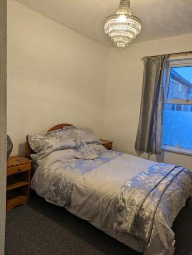纽波特Cozy flat的一间卧室配有一张床、一个吊灯和一扇窗户