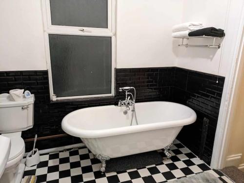 纽波特Cozy flat的浴室铺有 ⁇ 格地板,配有白色浴缸。
