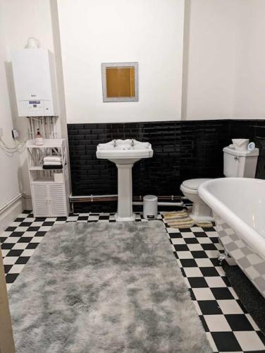纽波特Cozy flat的一间带水槽、浴缸和卫生间的浴室