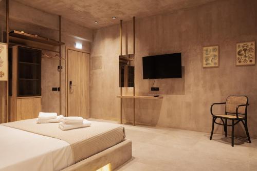 新马尔马拉斯Medusa Luxury Suites的一间卧室配有一张床、一台电视和一把椅子