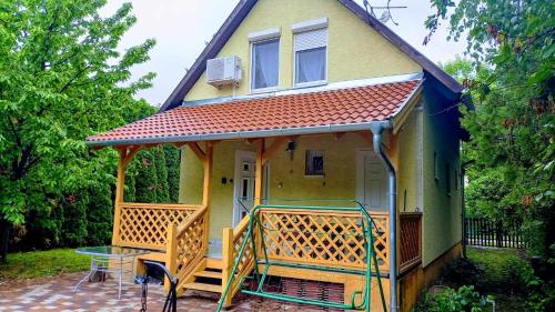 韦伦采Strandközeli Babu-házunk kiadó!的一座黄色的小房子,设有甲板和桌子