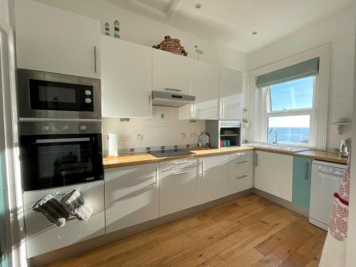 文特诺Sandy Toes - awesome beach view and access的一间厨房,配有白色的橱柜和大窗户