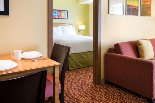 斯科茨Sonesta Simply Suites Phoenix Scottsdale的酒店客房设有一张床铺、一张桌子和一间卧室。