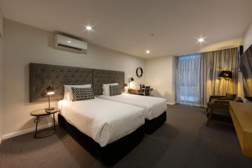 堪培拉堪培拉大道酒店的酒店客房设有一张大床和一张书桌。