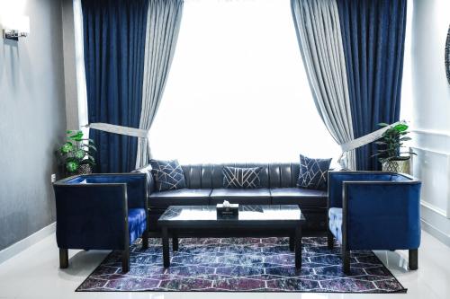 费萨拉巴德Oxygym Hotel Faisalabad的客厅配有黑色沙发和蓝色椅子
