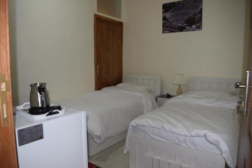 瓦迪穆萨Petra rose city的配有白色床单的酒店客房内的两张床