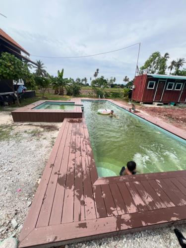 甲抛峇底HOMESTAY Kampong KOTA AUR Resort with swimming pool, Kepala Batas, SEBERANG PERAI, PENANG -MOTAC registered Awarded ASEAN homestay standard Malaysia AWARD 2023-2025 Only 3 minutes from viral KG AGONG的男人在带木甲板的游泳池游泳