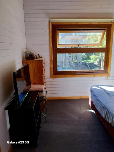 拉安戈斯图拉镇Antares的一间卧室配有一张床、一张书桌和一个窗户。