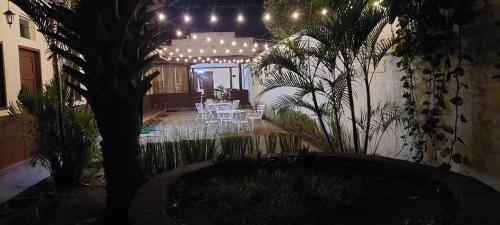 El VenadoHotel Sansivar的庭院配有白色桌子和树灯。