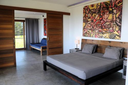 乌鲁瓦图乌鲁瓦图阿万别墅的卧室配有一张床,墙上挂有绘画作品