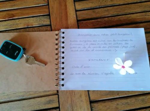 普纳奥亚Bungalow Moemoea的一本笔记本,上面有一把钥匙和一朵花