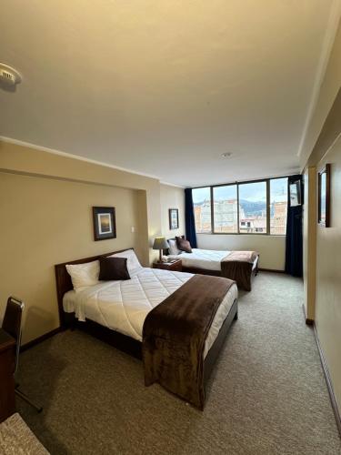 昆卡Hotel Presidente by NASS的酒店客房设有两张床和大窗户。