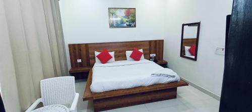 古尔冈The Grace Residency的一间卧室配有一张带红色枕头和镜子的床