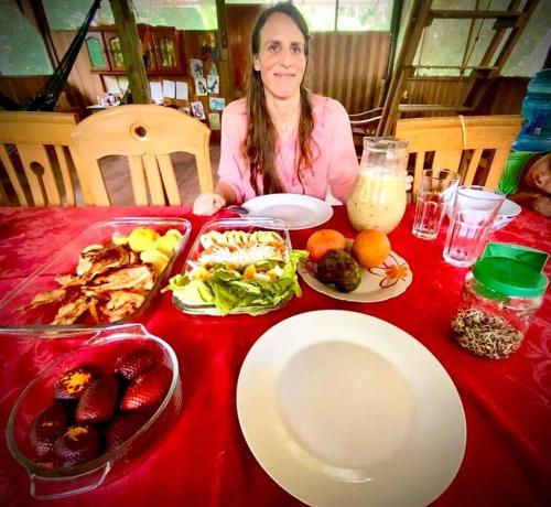 普卡尔帕Jungle Lodge with lookout tower的坐在餐桌上吃一盘食物的女人