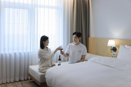 仁川市Aank Hotel Incheon Guwol的坐在床边的男人和女人