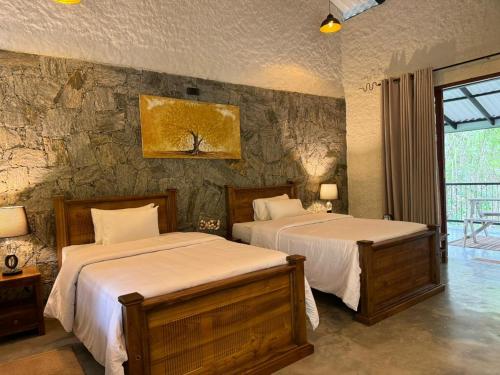 GinigathenaArsulana Eco Lodge & Spa的一间卧室设有两张床和石墙