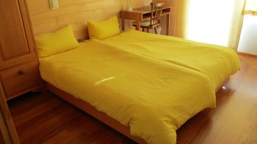 The Healthy Guesthouse的一张黄色的大床,配有黄色床单和枕头