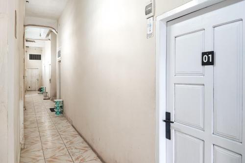 PaalmerahRedDoorz Syariah near Transmart Jambi的一条空的走廊,有白色的门,铺着瓷砖地板