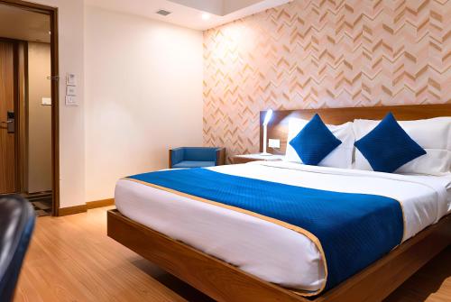 新德里The Orion Plaza - Nehru Place的一间卧室配有一张带蓝色枕头的大床