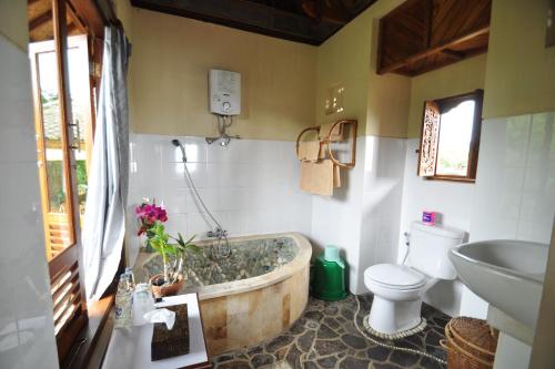 姆杜克Puri Lumbung Cottages Restaurant & Spa Munduk的带浴缸、卫生间和盥洗盆的浴室