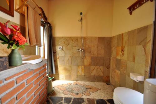 姆杜克Puri Lumbung Cottages Restaurant & Spa Munduk的带淋浴、卫生间和盥洗盆的浴室