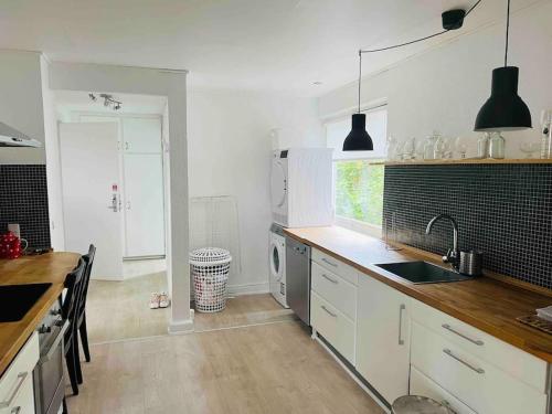 奥胡斯Lovely 1-bedroom condo in Aarhus C的厨房配有白色橱柜、水槽和洗碗机。