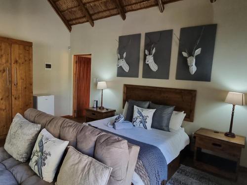 侯斯普瑞特Paradise River Lodge的卧室配有一张床和一张长沙发,墙上挂着鹿角