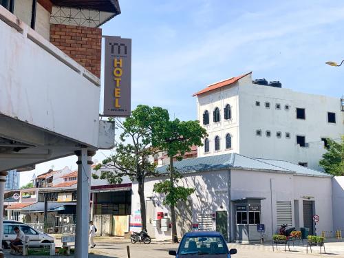 马六甲Mana Mana Hotel • Melaka •的停在白色建筑前面的汽车