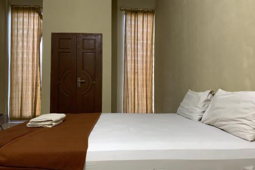 ToloOYO 93876 Athirah Kost的卧室配有一张带两个枕头的大白色床