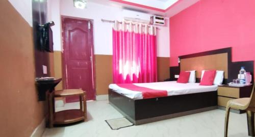 普里Hotel Samrat Palace Puri Near Sea Beach Excellent Service的一间卧室配有一张粉红色墙壁和红色门的床