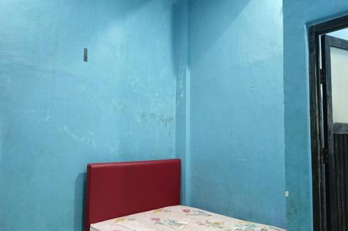 PallengukOYO 93875 Tifar House的蓝色墙壁房间内的红色椅子