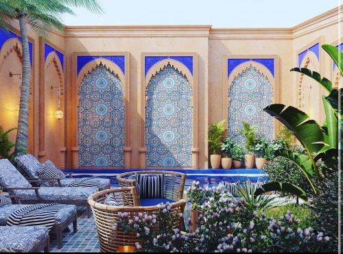 塔什干Hamsa Butique Hotel Tashkent的庭院设有椅子和植物,铺有蓝色和白色瓷砖