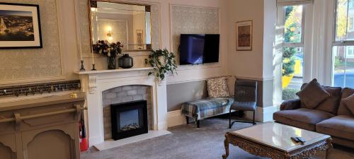 利明顿温泉Victoria Park Lodge & Serviced Apartments的客厅设有壁炉和电视。