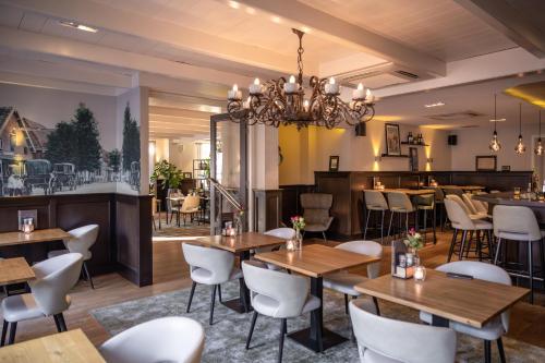 阿斯米尔Hotel Aalsmeer的配有木桌和白色椅子的餐厅