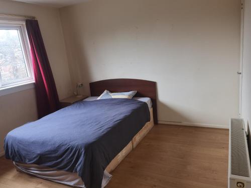 格拉斯哥Glasgow Double Room Free Parking的一间卧室配有一张带蓝色棉被的床和窗户。