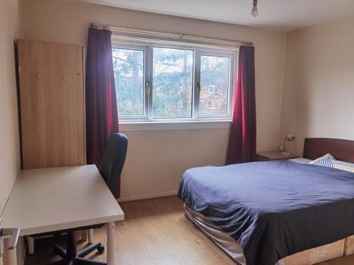 格拉斯哥Glasgow Double Room Free Parking的一间卧室配有一张床、一张书桌和一个窗户。