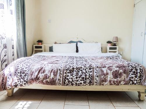 内罗毕3BR Serene Bungalow in Lower Kabete的一间卧室配有一张带紫色床罩的床