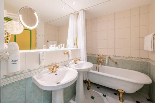 宾茨罗嘉德温泉海滩酒店的浴室配有2个盥洗盆、浴缸和浴缸。