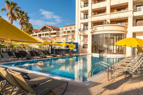 马赛金色郁金香马西利亚别墅酒店的一座带椅子和遮阳伞的游泳池位于一座建筑旁边