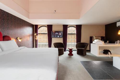 豪达Relais & Châteaux Weeshuis Gouda的一间卧室配有一张床、一些椅子和窗户