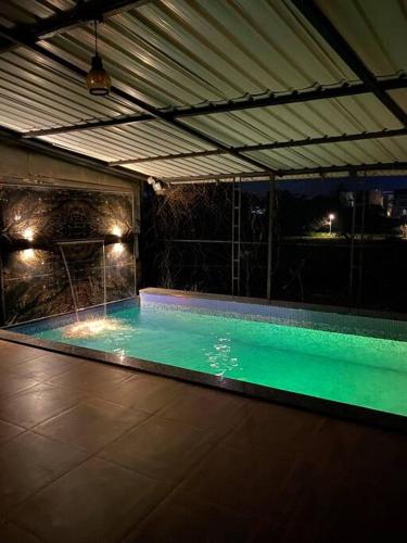 罗纳瓦拉Imagine Harmony的室内游泳池,晚上提供绿水